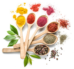 Assortment of colorful spices in the wooden spoons on the white