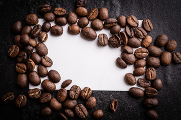 roasted coffee beans with blank paper on dark background, can be used as a background