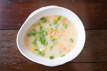 Congee with green vegetable in white bowl