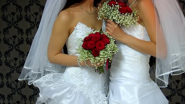 Wedding lesbians girl in bridal dress kissing. Wallpaper in background. Happy lesbians wedding.