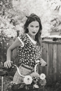 Young pinup woman cycling in fields under bright blue summer sky copy space image