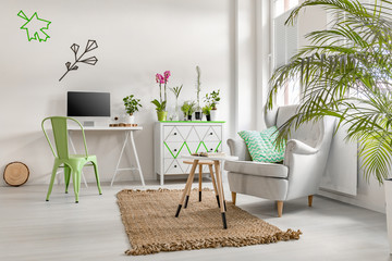 Bright living room interior with home plants, commode and cosy armchair