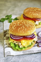 Cheeseburger with chicken salad and fresh vegetables.