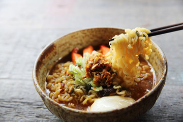 Noodles with egg spicy soup on wood background