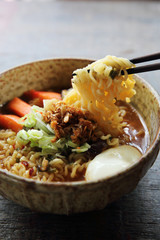 Noodles with egg spicy soup on wood background