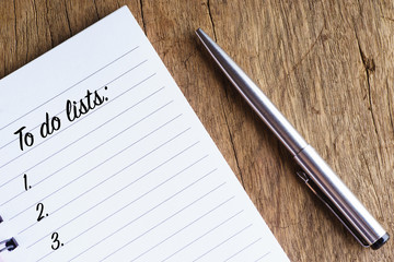 "To do lists" words on notebook with pen near it on wooden background - business and to do conceptual
