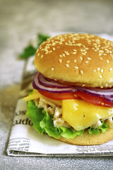 Cheeseburger with chicken salad and fresh vegetables.