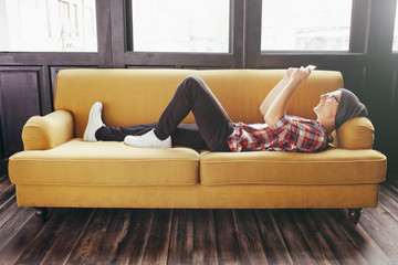 young man relaxing on sofa and looking at his smart phone