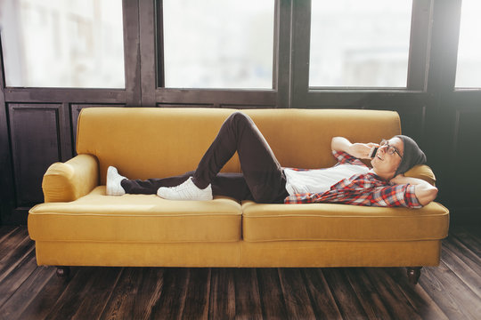 young man relaxing on sofa and talking his smart phone