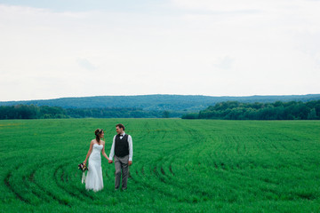 Fototapeta premium the bride and groom with a bouquet on the green field