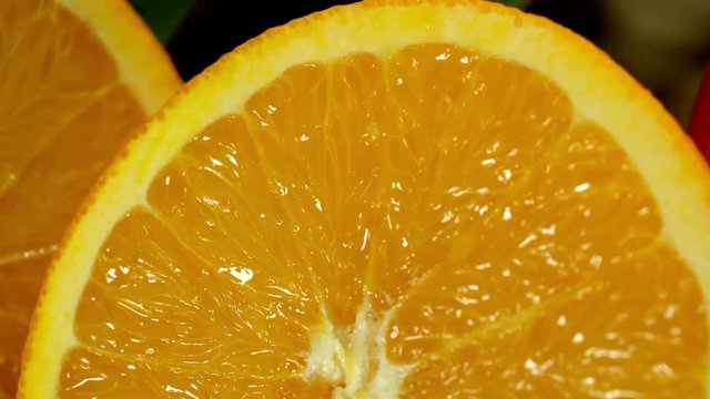 Group of oranges with leaves on wooden boards. Orange cut in half. Camera moves from left to right. Cross section.