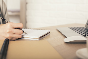 Woman writing in notepad closeup