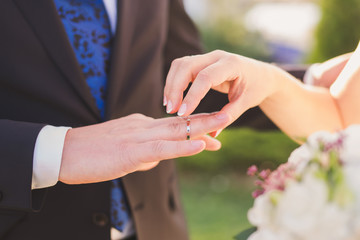 Obraz na płótnie Canvas closeup of a bride put a wedding ring onto the groom's finger