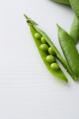 Fresh green peas on white wood