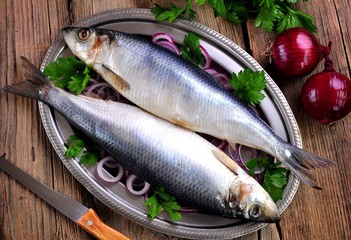 salted herring with red onion and parsley on the old wooden background.