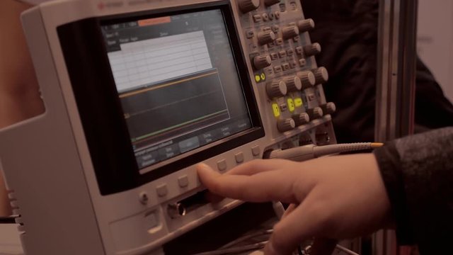 Scientist working with an electronic measuring device and see the results in the form of sine waves on the display equipment