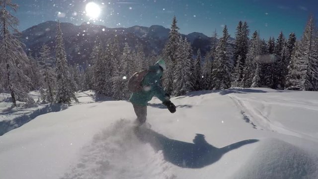 FOLLOW: Female freeride snowboarder doing powder turns in fresh snow off piste
