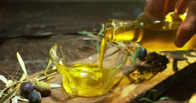 Genuine Italian organic oil cold pressed in slowmotion falls on organic bread. concept of nature and healthy food, healthy and natural. fresh olives and Tuscan Italian oil