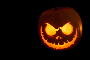 Scary Halloween pumpkin isolated on a black background. Scary glowing face trick or treat