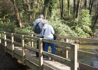 Mature couple standing on a bridge on a woodland area. 