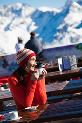 femme souriante sur une terrasse à la neige avec une tasse de café
