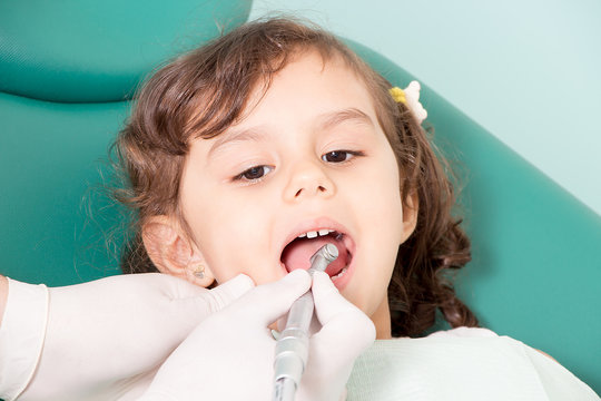 Dentist examining girl's teeth at dental clinic