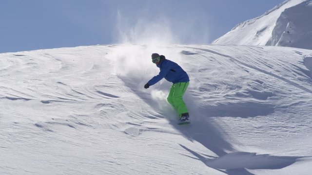 SLOW MOTION: Extreme snowboarder doing powder turn in fresh mountain snow