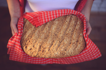 Woman baker holding freshly baked bread - Home meade bun of brea