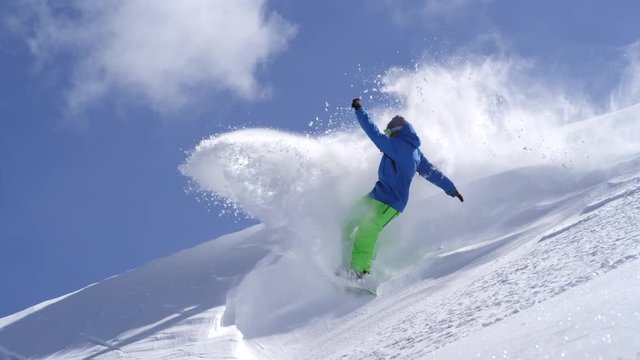SLOW MOTION CLOSE UP: Snowboarder doing powder turns spraying snow on a mountain
