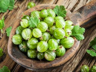 Gooseberries in the wooden bowl on the table.