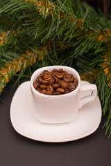 Coffee beans in a white cup and fir branch