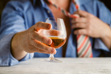 handsome young man in suit tasting with glass of alcohol