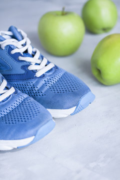 Sport shoes and apples on gray concrete background