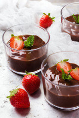 Chocolate mousse with strawberries in glass on rustic table