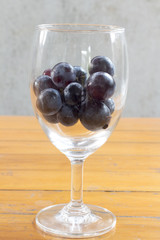 Grapes in a wine glass on a wooden table.