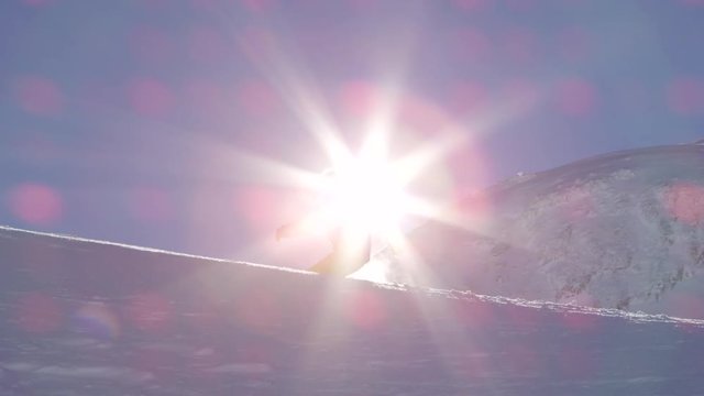 SLOW MOTION: Snowboarder snowboarding in fresh snow doing powder sprays over sun