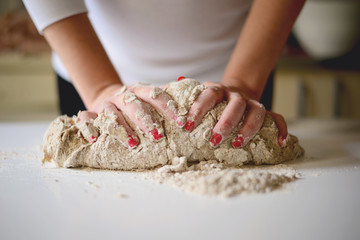 Woman's hands knead dough on a table