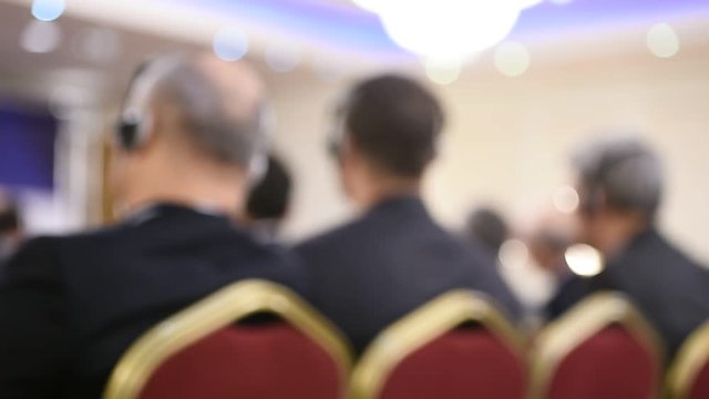 Unrecognizable person using in ear headphones for translation during event