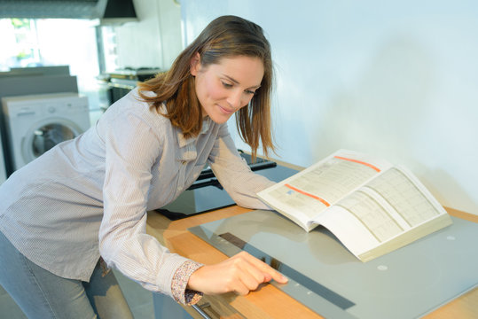Woman holding instruction book and programming hob