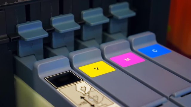 A row of four color cartridges in inkjet printer - black, yellow, red (magenta), blue. Closeup
