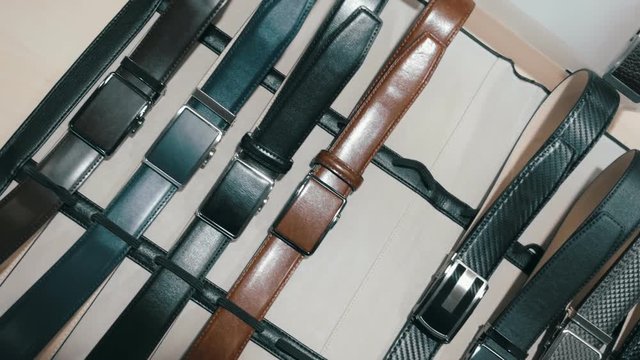 A new collection of leather belts for trousers in a shop. Camera in motion