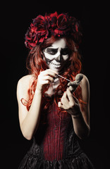 Young voodoo witch with calavera makeup (sugar skull) piercing doll