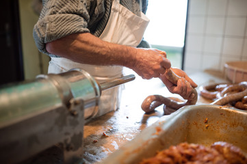 Man making sausages the traditional way using sausage filler.