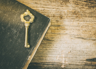 Vintage key over an old book on wooden background, Vintage color tone can be used for your text or...