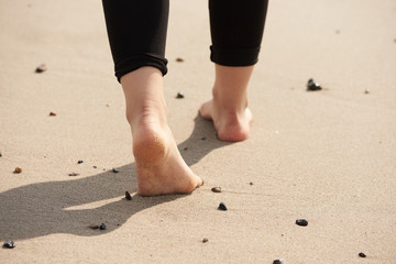 Füße einer jungen Frau am Strand.