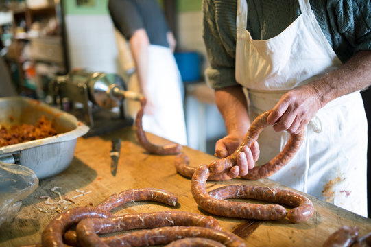 Men making sausages the traditional way using sausage filler.