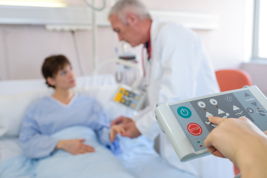 Doctor with patient, closeup of hand on bed controller