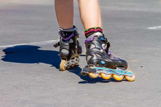 Close-up of female legs in roller skating on asphalt