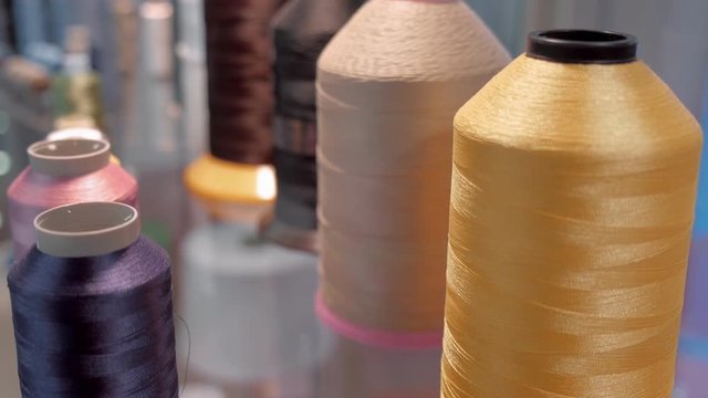 Rows spools of thread of different colors on a shelf in a store