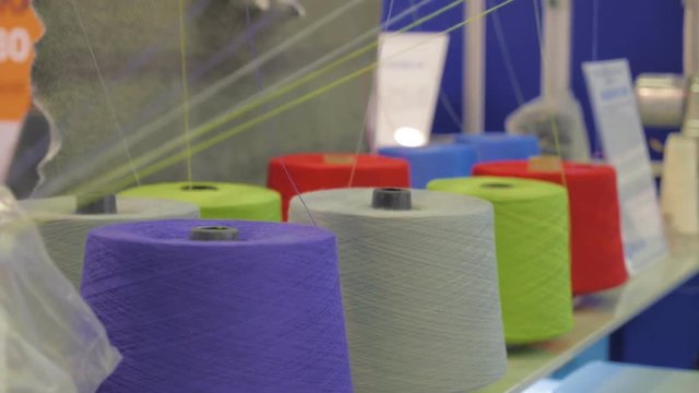 Rows spools of thread of different colors in the industrial sewing machine. Different parts of the sewing machine. Yarn tensioning system in the sewing equipment